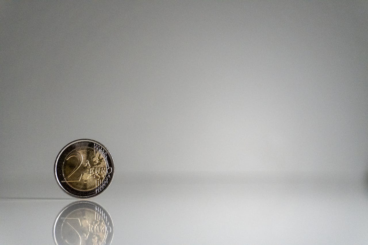 A minimalist image of a 2 euro coin with reflection on a sleek surface.